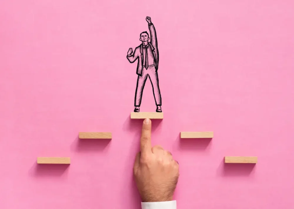Illustration de la progression professionnelle : un manager soutient un collaborateur sur une plateforme en bois, symbolisant l'accompagnement RH et l'amélioration de la performance au travail.